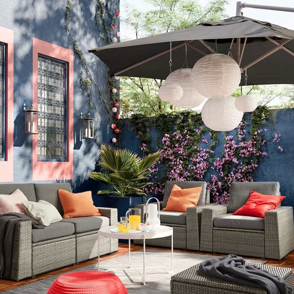 IKEA SOLLERÖN outdoor seating solution with removable dark grey covers in a colourful outdoor space with deep blue walls.