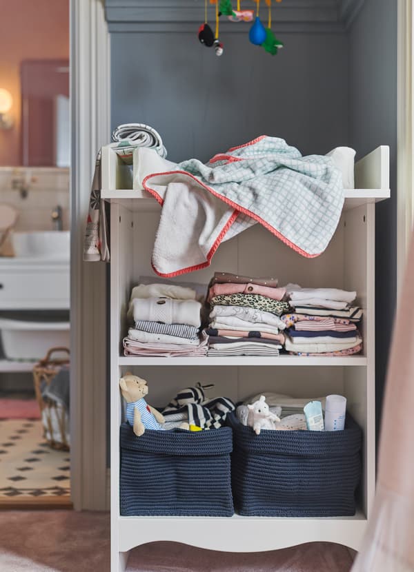 IKEA STUVA changing table up against a wall with NORDRANA blue woven baskets holding toys and changing supplies.