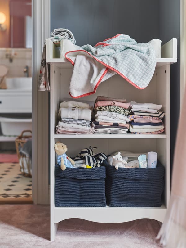 IKEA STUVA changing table up against a wall with NORDRANA blue woven baskets holding toys and changing supplies.