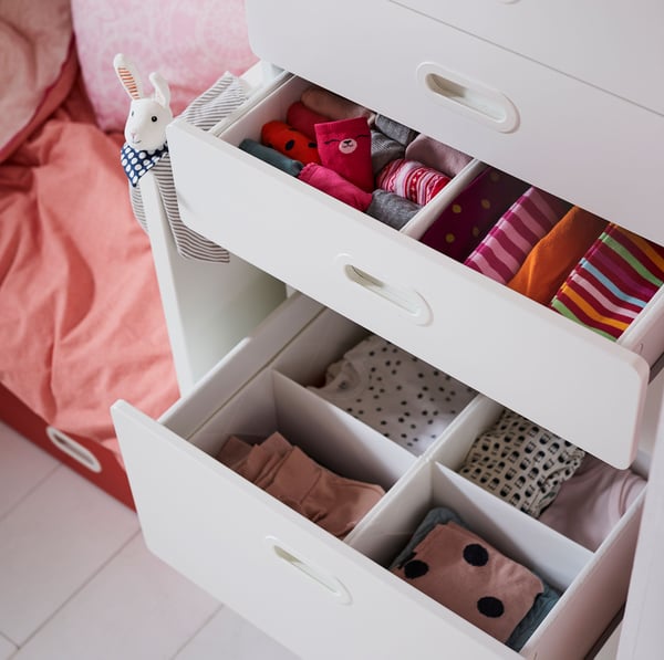 IKEA STUVA dresser drawer unit with RASSLA insert organisers inside, storing baby clothes and accessories.