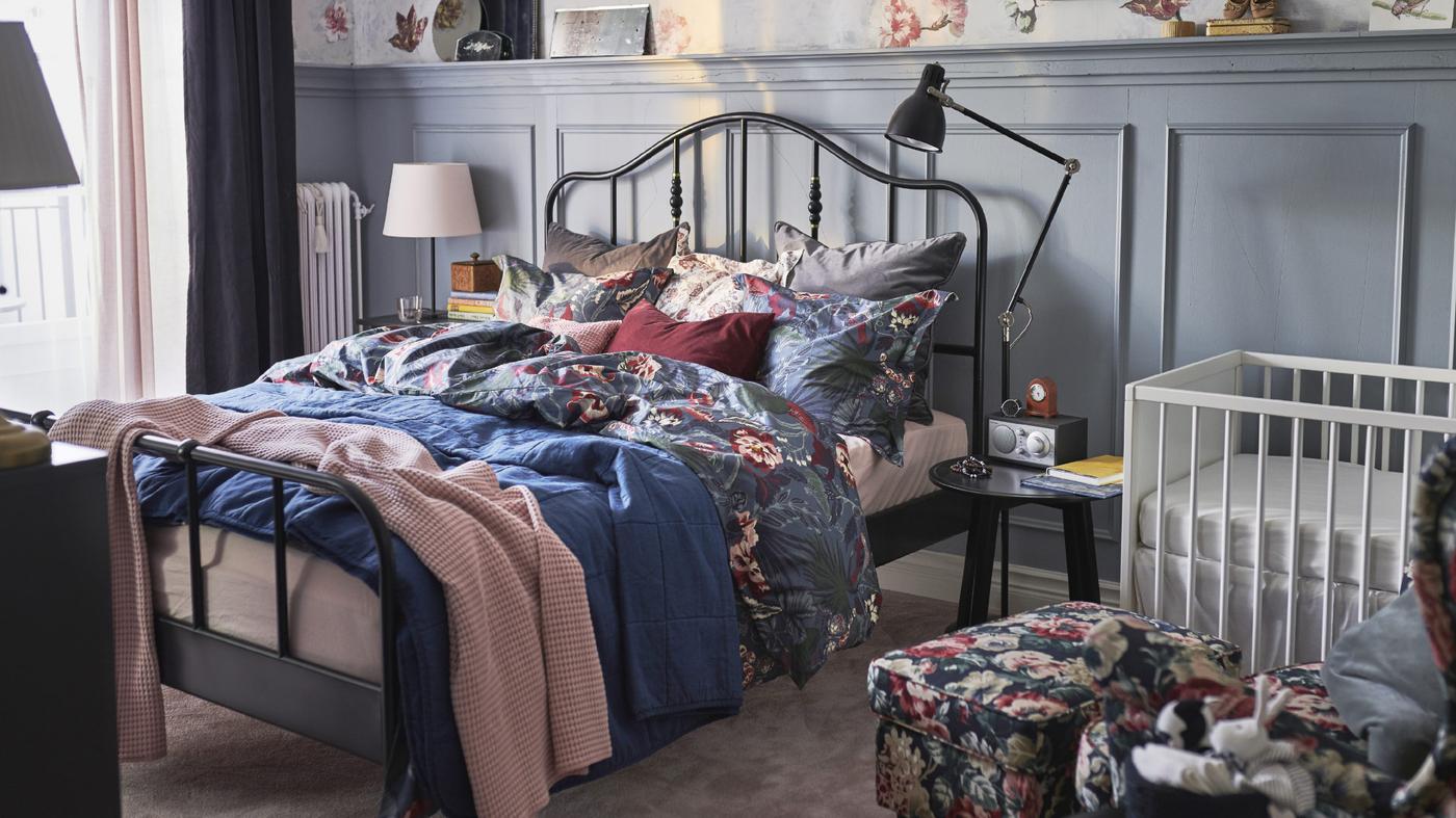 IKEA STUVA white cot and changing table, with SAGSTUA black bedframe in a small bedroom with a traditional feel.