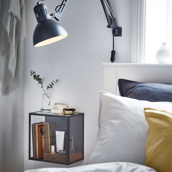 IKEA TERTIAL tamnosiva radna lampa, s podesivom ručicom i BARKHYTTAN kutija za izlaganje pored uzglavlja kreveta.