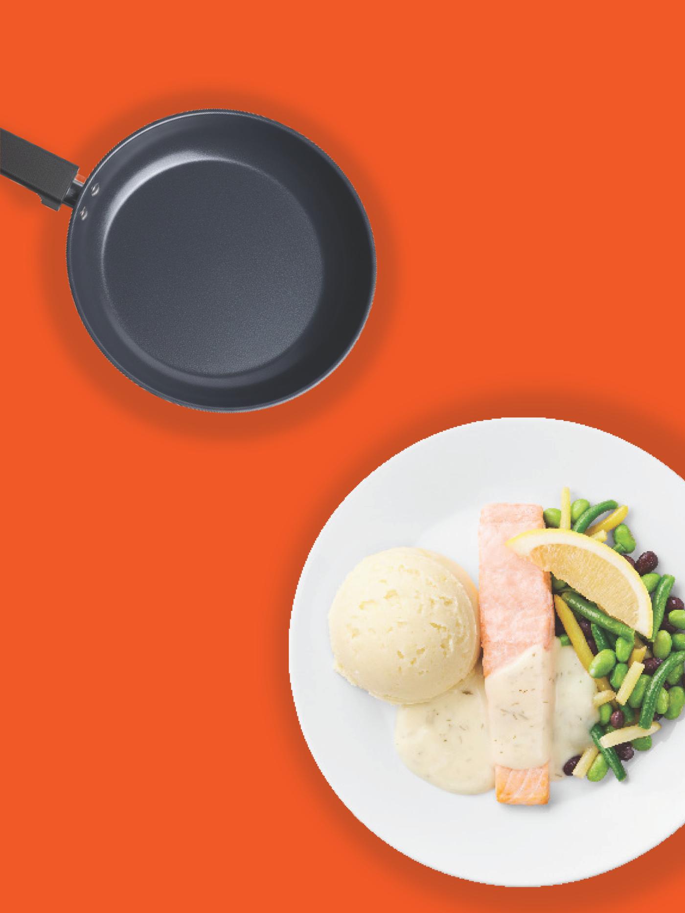 IKEA tiganj i beli tanjir sa lososom, pireom od krompira, zelenim povrćem i kriškom limuna na jarko narandžastoj pozadini, koji sugerišu lako kuvanje i ukusno serviranje kod kuće.