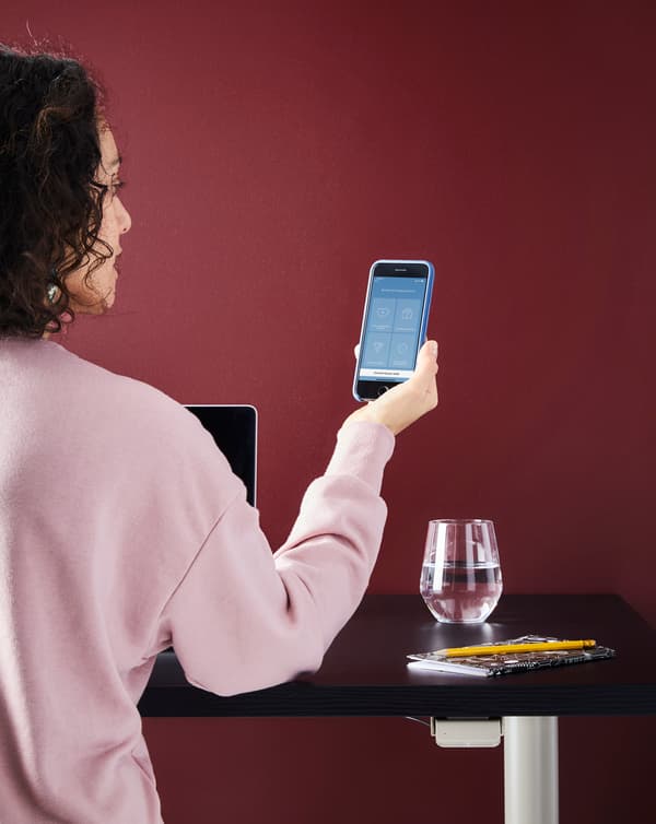 IKEA - Tornada a l'activitat - Dona mirant el mòbil en un escriptori