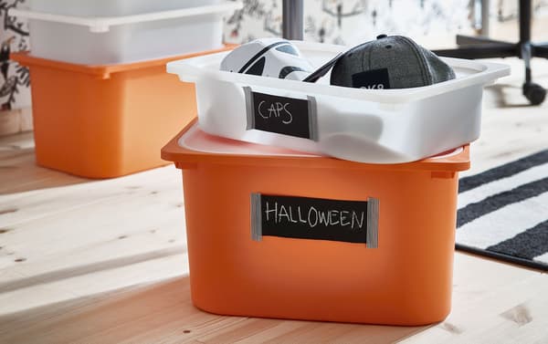 IKEA TROFAST orange and clear plastic storage boxes with black labels, holding caps.