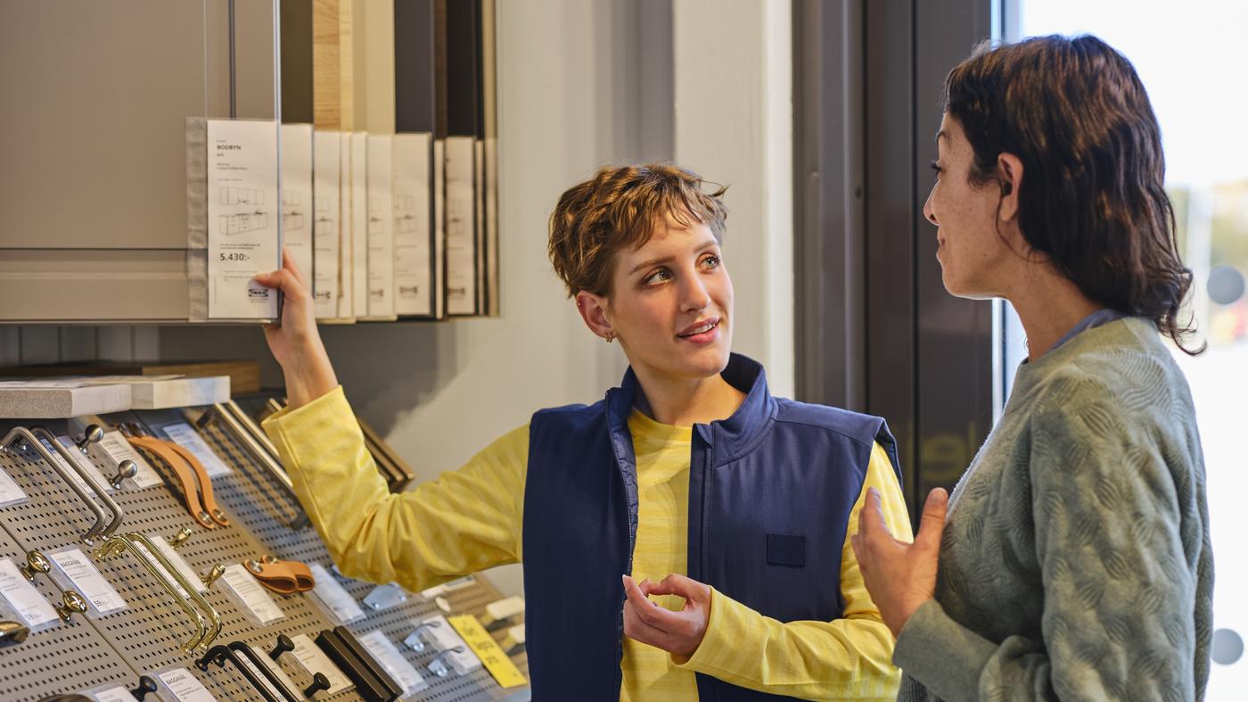IKEA-työntekijä auttaa asiakasta tavaratalossa.