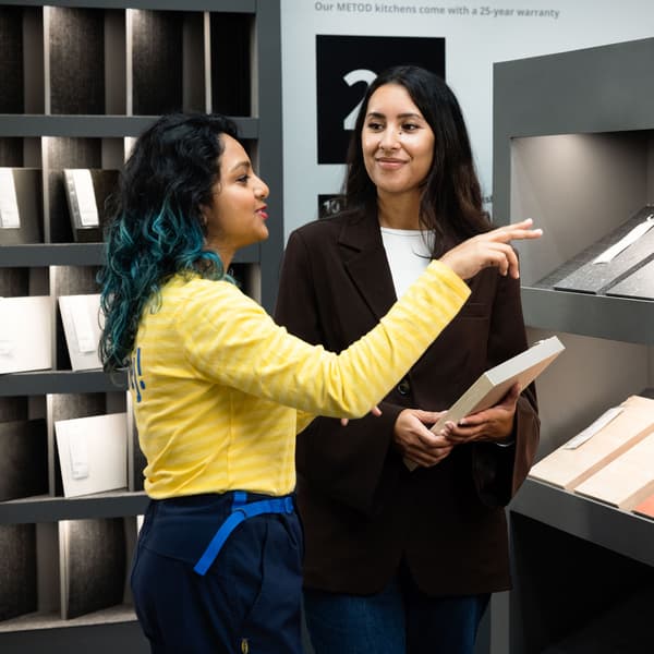 IKEA-työntekijä esittelee asiakkaalle keittiön työtasonäytteitä myymälässä.