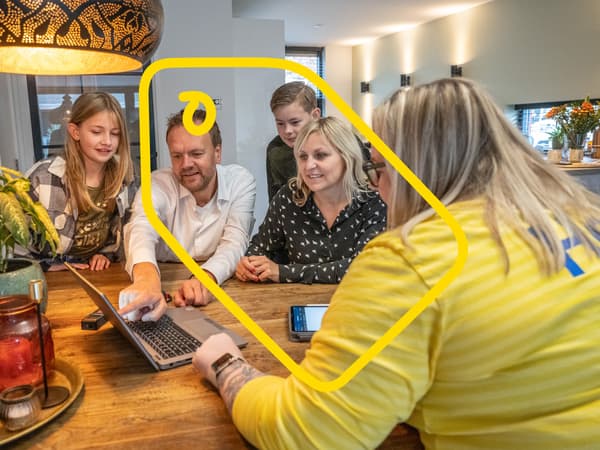 IKEA-työntekijä käymässä keittiösuunnitelmaa läpi asiakasperheen kotona ison puisen pöydän ääressä.