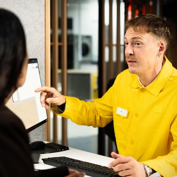 IKEA-työntekijä näyttää asiakkaalle monitoriin piirretyn keittiön.