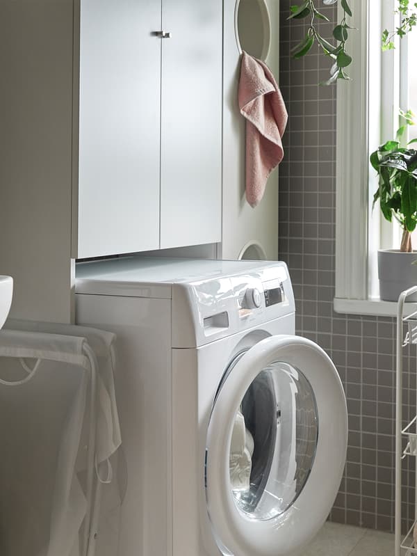 IKEA UDDARP washing machine, a HORNAVAN trolley and a NYSJÖN cabinet, all in white, are standing next to window.