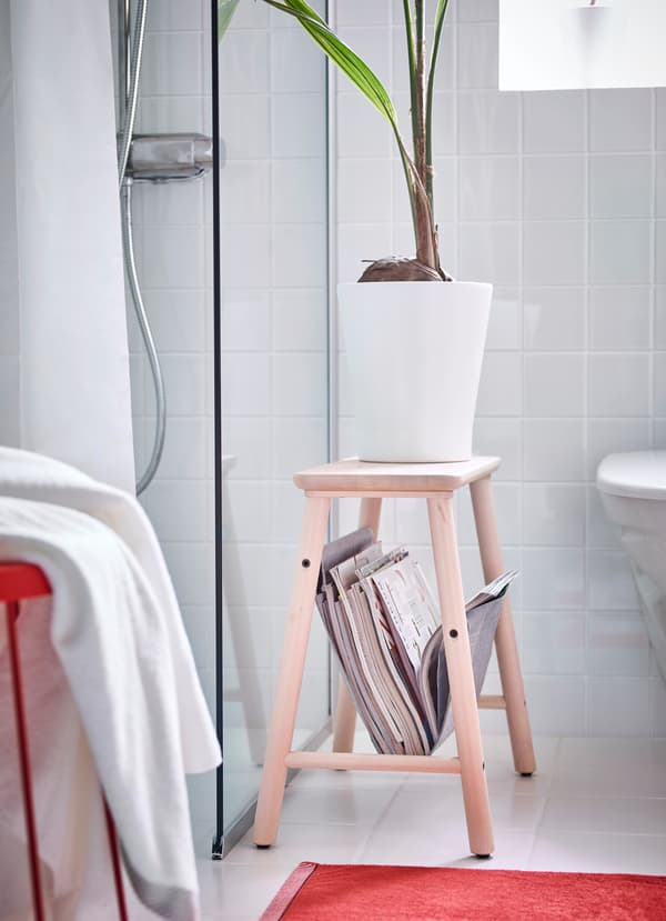 IKEA VILTO light birch wood storage stool is 45 centimeters in height and has a grey felt sling underneath the seat to store magazines and books in the bathroom.