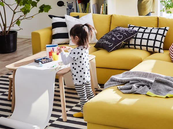 IKEA VIMLE 빔레 3인용 소파 섹션 옆에서 커피테이블 위에 올려진 긴 두루마리 종이에 그림을 그리고 있는 여자아이