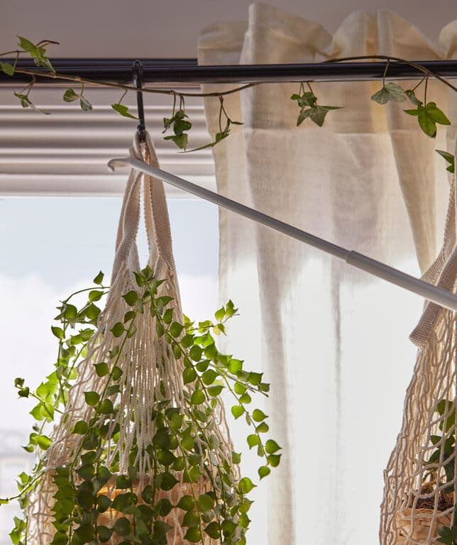 IKEA Vorhangstange mit beige-transparentem Vorhang und dekorativ hängender Pflanze im Makramee-Pflanzenhalter. Urban Jungle Dekoration mit frischen Grünpflanzen vor hellem Fenster – ideal für modernes, natürliches Wohndesign