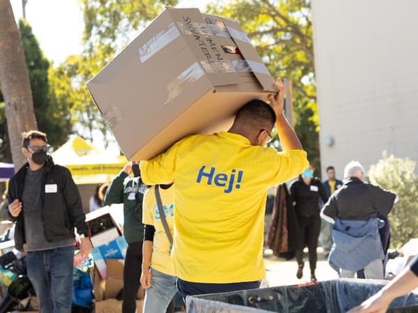 IKEA worker in yellow shirt with "Hej!" logo carrying a box