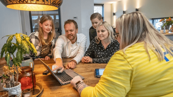 Ikea zaposlenik u prednjem planu razgovara s četveročlanom obitelji u pozadini, a svi gledaju u računalo.