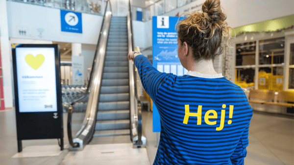 イケアのコワーカーが入り口でエレベーターを指さしている