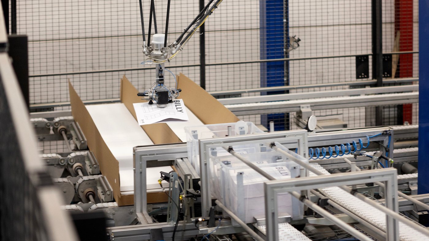 IKEA's BILLY bookcase is manufactured in a factory. A robot puts assembly instructions in a flat package with a bookshelf.