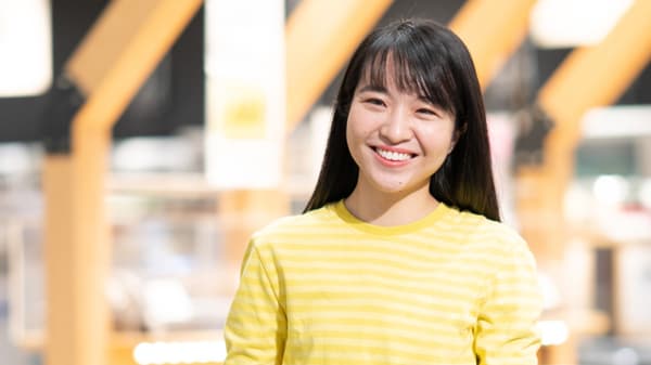 イケアストアの売場を背景に、黄色いボーダーのトップスを着た人物の上半身ポートレート