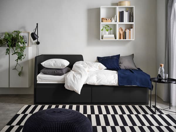 黒い収納付きベッドに白とネイビーの寝具を合わせたモダン寝室。ストライプラグでスタイリッシュな空間。