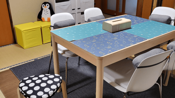 青いクロスが敷かれたテーブルに椅子が並んでいる。