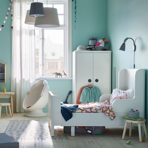 Il letto allungabile e il guardaroba in bianco della serie BUSUNGE, insieme al tavolo per bambini in legno chiaro FLISAT, trasformano la stanza in un parco giochi divertente ma sicuro – IKEA