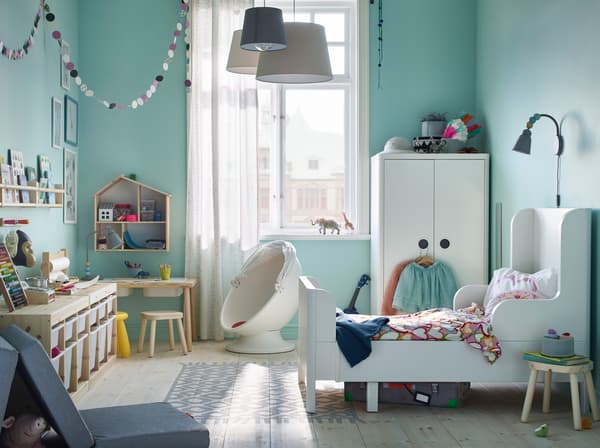Il letto allungabile e il guardaroba in bianco della serie BUSUNGE, insieme al tavolo per bambini in legno chiaro FLISAT, trasformano la stanza in un parco giochi divertente ma sicuro – IKEA