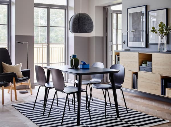 Il tavolo LISABO, facile da montare, e le sedie SVENBERTIL in nero creano una combinazione di stile al centro di una stanza con pareti grigie e bianche e scaffali in frassino che alternano elementi a giorno e con ante – IKEA