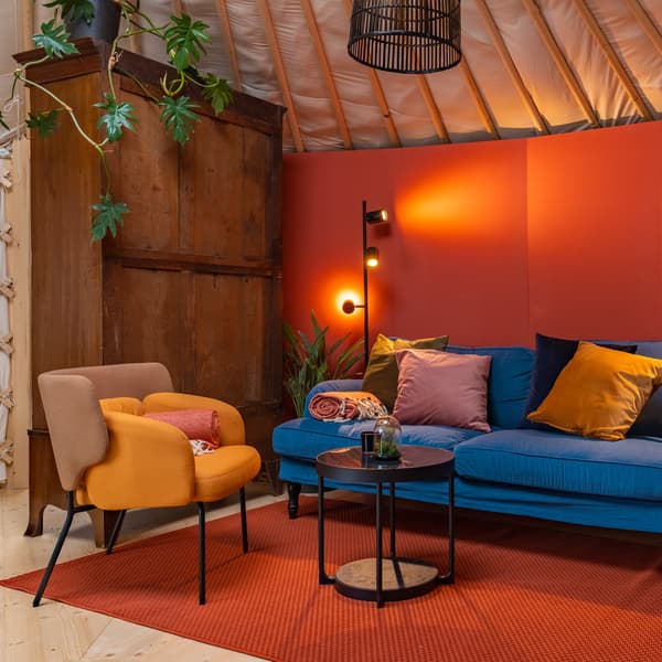 Im Ruhebereich einer Sauna-Cube-Anlage stehen ein gemütliches IKEA Sofa und Sessel in fröhlichen Farben. 