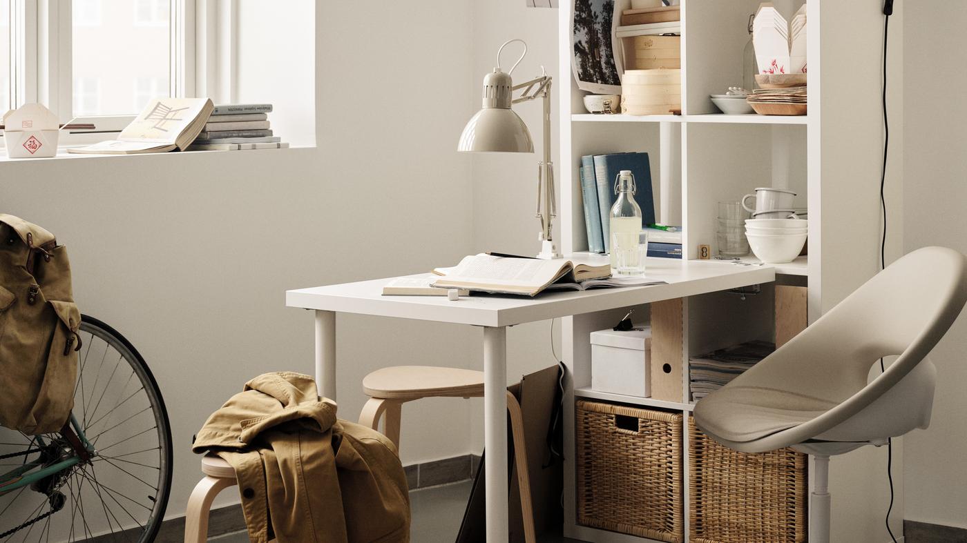 Image depicted flexible 'work from home' set up with white desk attached to open shelving unit and stools and chair surrounding