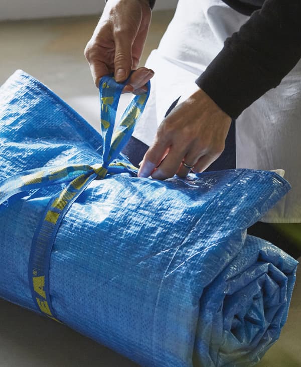 Image of a blue picnic blanket made from FRAKTA blue bags and tea towels rolled up and tied using the handles from the bag
