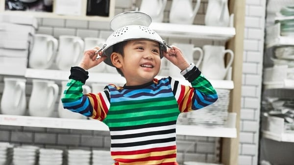 Image of a little boy wearing a striped shirt placing a colander on top of his head