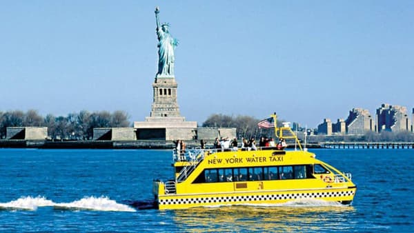 image of a water taxi with the statue of liberty in the background