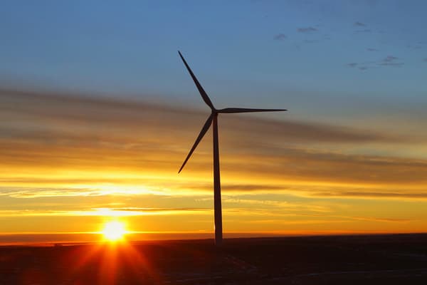 Image of a wind turbine in silhouette against a sunset.