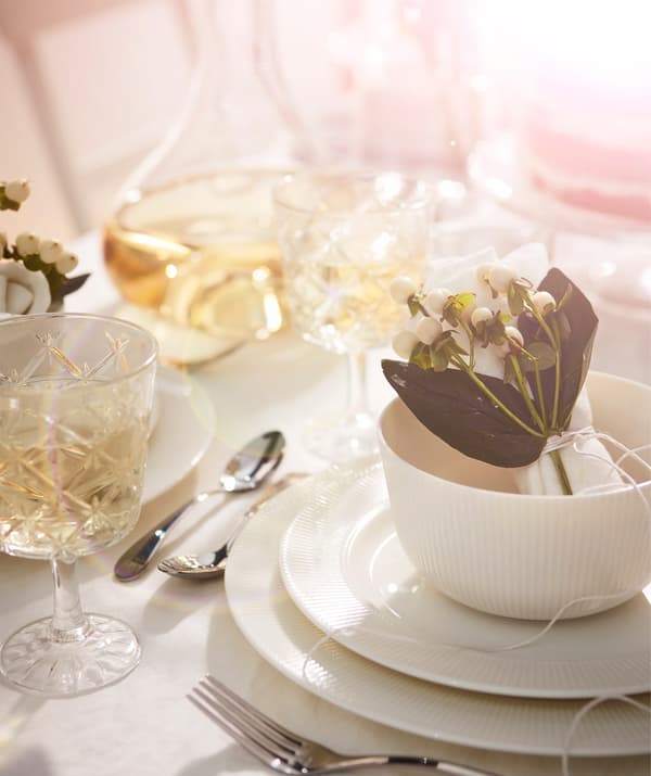 Image of individual place setting in all white, with glasses, tableware and floral decorations creating a feeling of luxury.