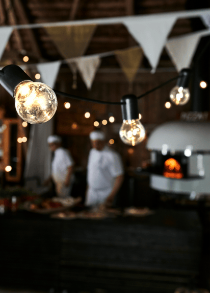 Image of lightbulbs and bunting in focus with two chefs in the background