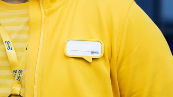 Imagen acercada del uniforme de un colaborador amarillo con un pin con una nube para poner el nombre.