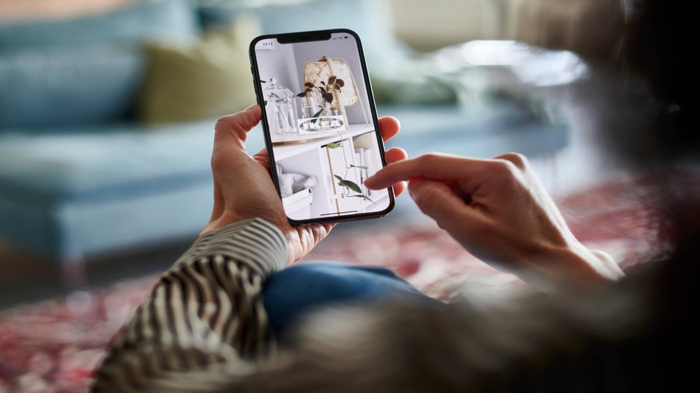 Imagen de persona viendo su celular con logo IKEA