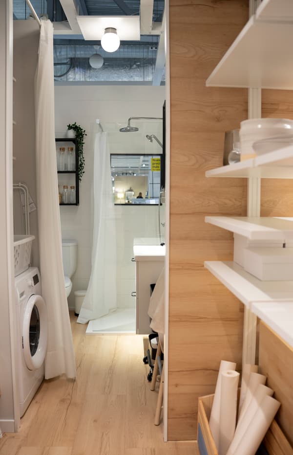 Imagen del baño del Contenedor al fondo, con la zona de lavadero y otro espacio para hobbies delimitado por una cortina blanca.