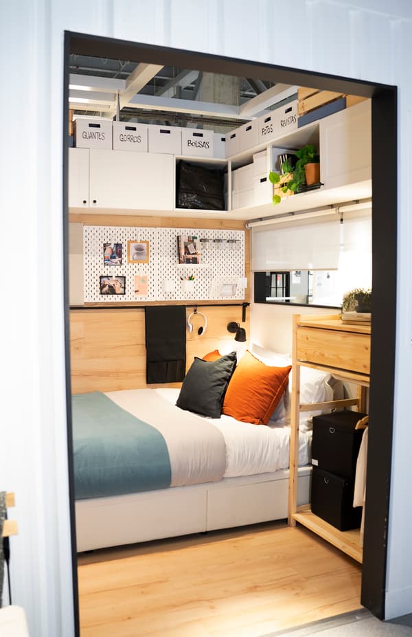 Imagen del dormitorio dentro del contenedor de transportes de 25 metros cuadrados con almacenaje vertical aprovechando cada espacio en las paredes.
