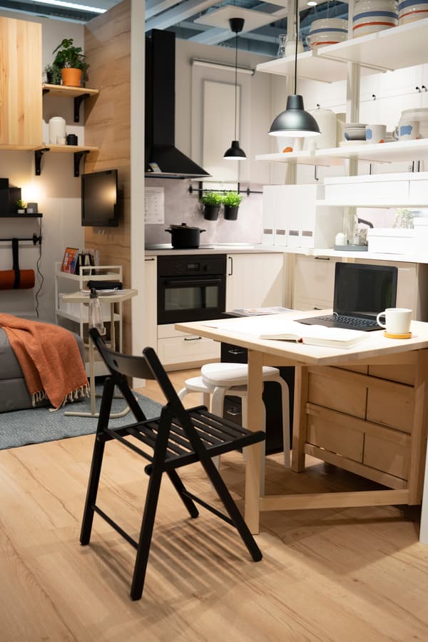 Imagen del saln y la cocina del contenedor de transportes donde vemos una mesa plegable que sirve como separador de espacios, alamacenaje y mesa de trabajo o comedor.