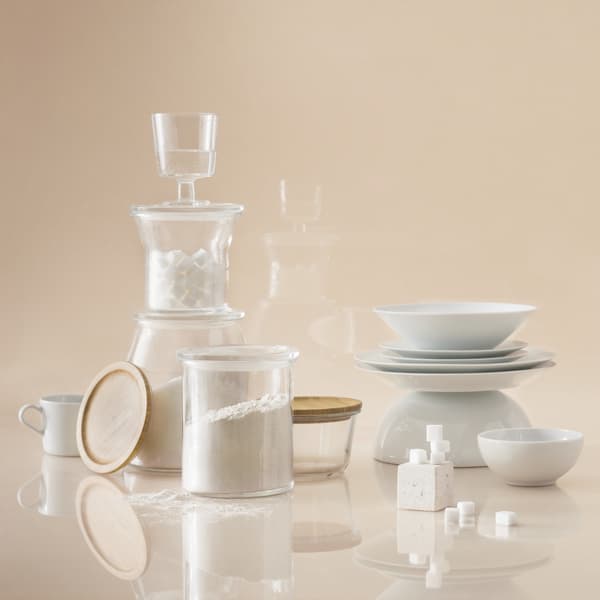 Imagen frontal de un set de vajilla y recipientes de cocina IKEA 365+ sobre un fonso y superficie beige. 