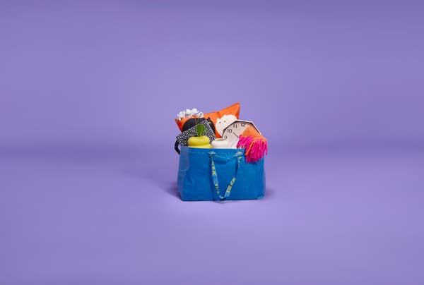 Imagen lila con bolsa FRAKTA en el centro con cosas en el interior.