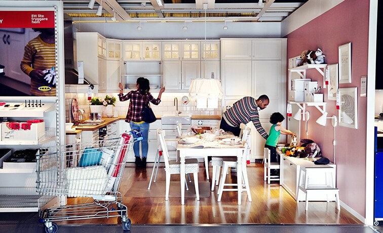 Imaginea prezintă un showroom IKEA cu mobilier de bucătărie și clienți. Se observă designul interior al magazinului și experiența de cumpărături oferită de IKEA.