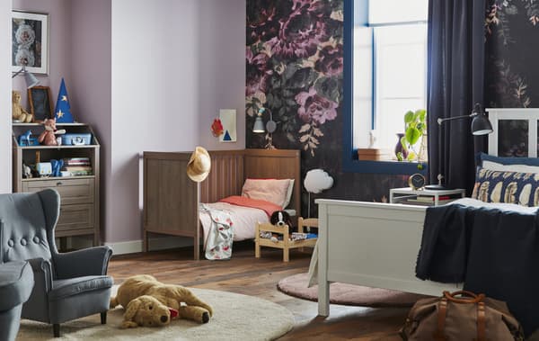 Imaxe dun dormitorio cunha cama dobre, un berce e xoguetes para nenos.