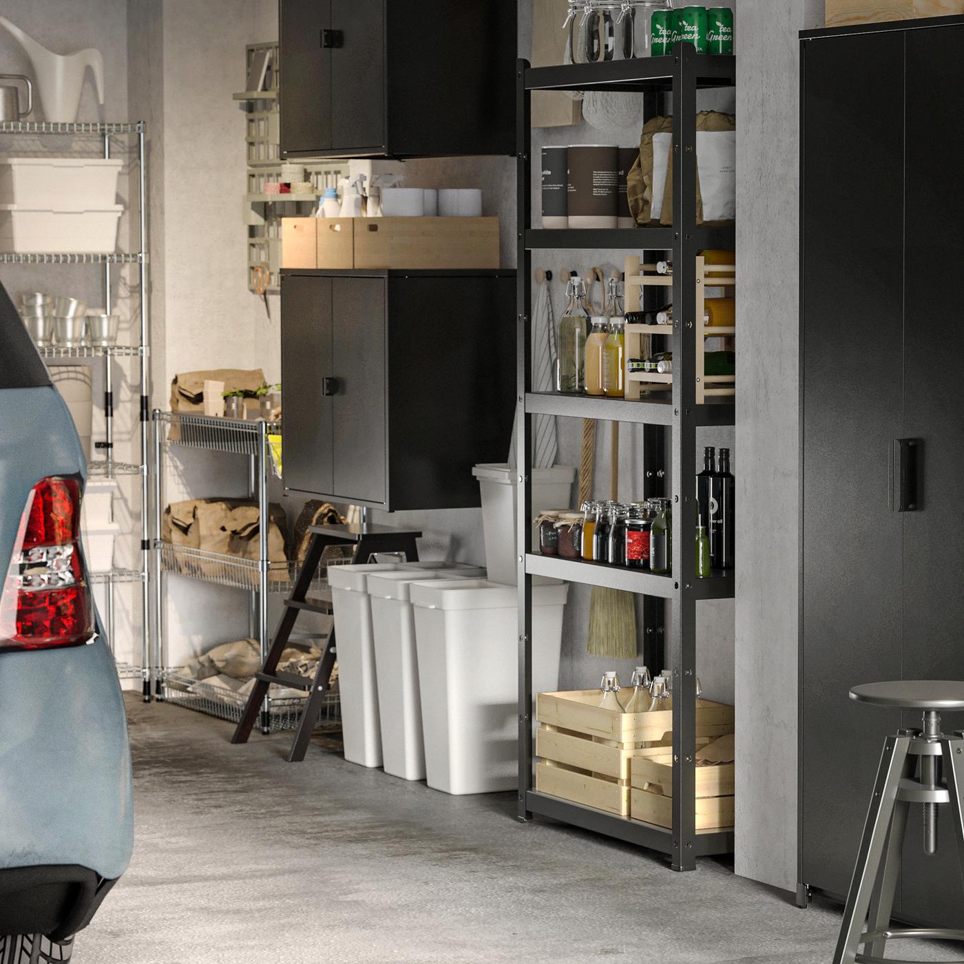 In a garage are black BROR open and closed storage cabinets. On the shelves are boxes and bottles. Underneath recycling bins.