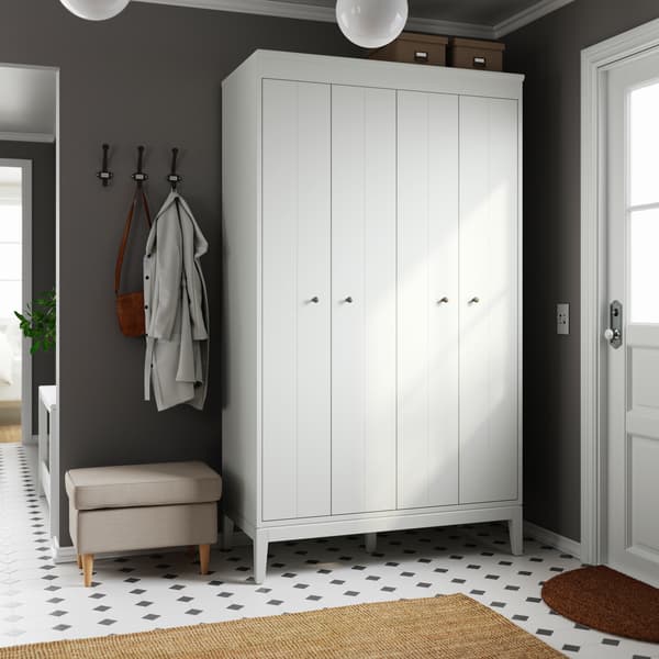 In a hallway with a black-and-white floor-tile pattern stands a white IDANÄS wardrobe. Stool by its side, thick rug below.