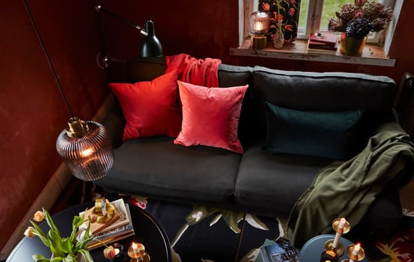 In a living room, a mix of pendant, floor and table lamps and a sofa with colourful cushions help set a warm, cosy mood.