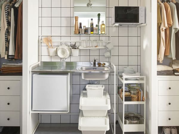 In a shared dorm room, a SUNNERSTA mini kitchen is sandwiched between two closets. Curtains hang in front of the closets.