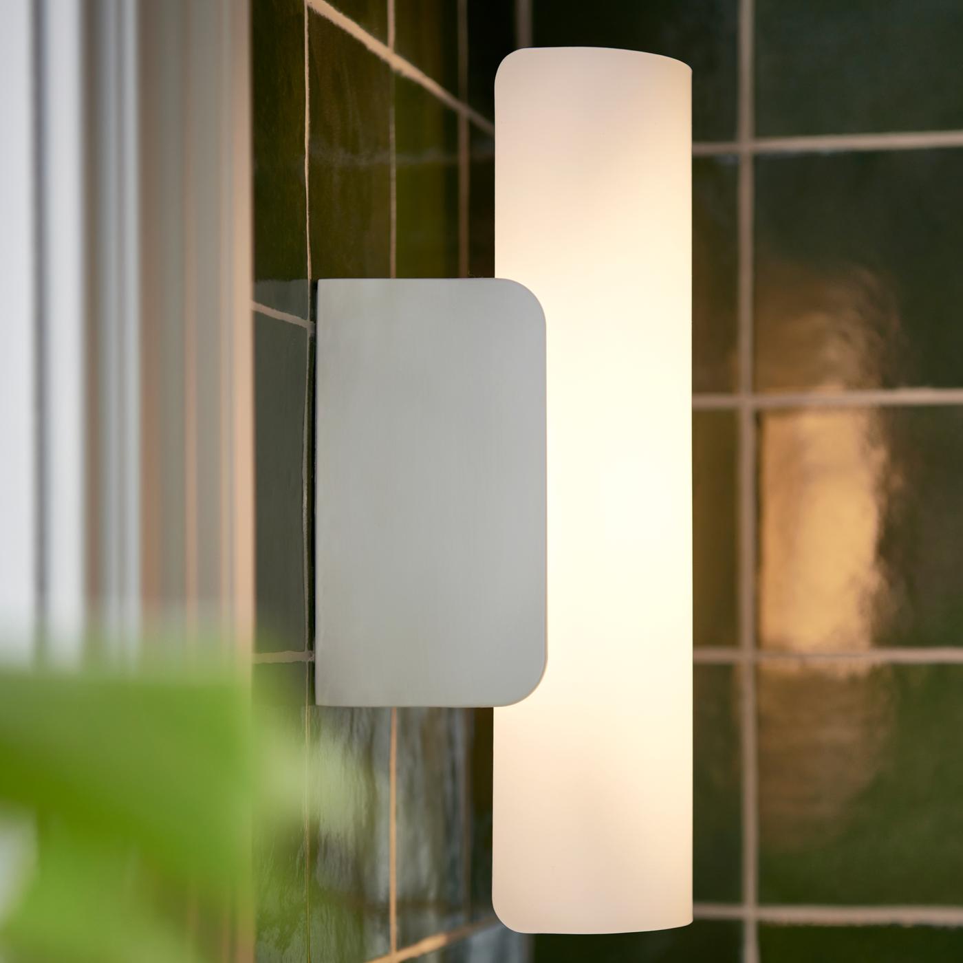 In einem grün gefliesten Badezimmer ist eine dimmbare HAVSDUN LED-Wandleuchte in Weiß/Frostglas Weiß zu sehen.