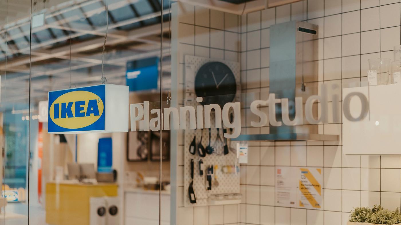 In einem IKEA Planungsstudio sieht man ein Schaufenster mit dem IKEA Logo, einer Küchenzeile und einem Planungsdesk.